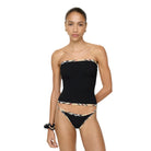 Woman wearing a black strapless bikini with patterned trim against a white background