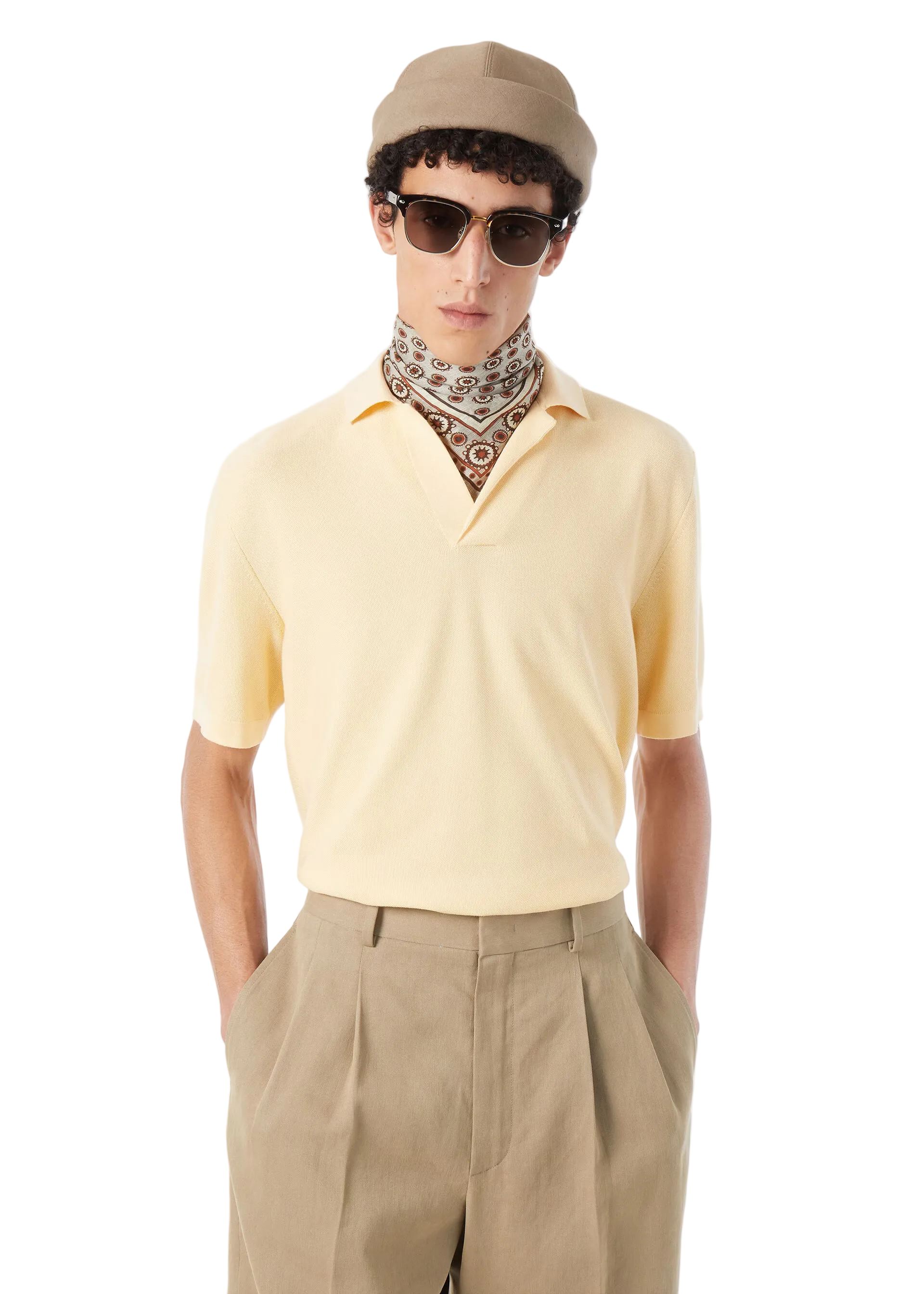 Man wearing a light yellow polo shirt, beige cap, sunglasses, and patterned scarf on a white background