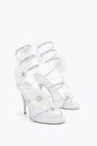 White high-heeled sandals with clear straps on a white background