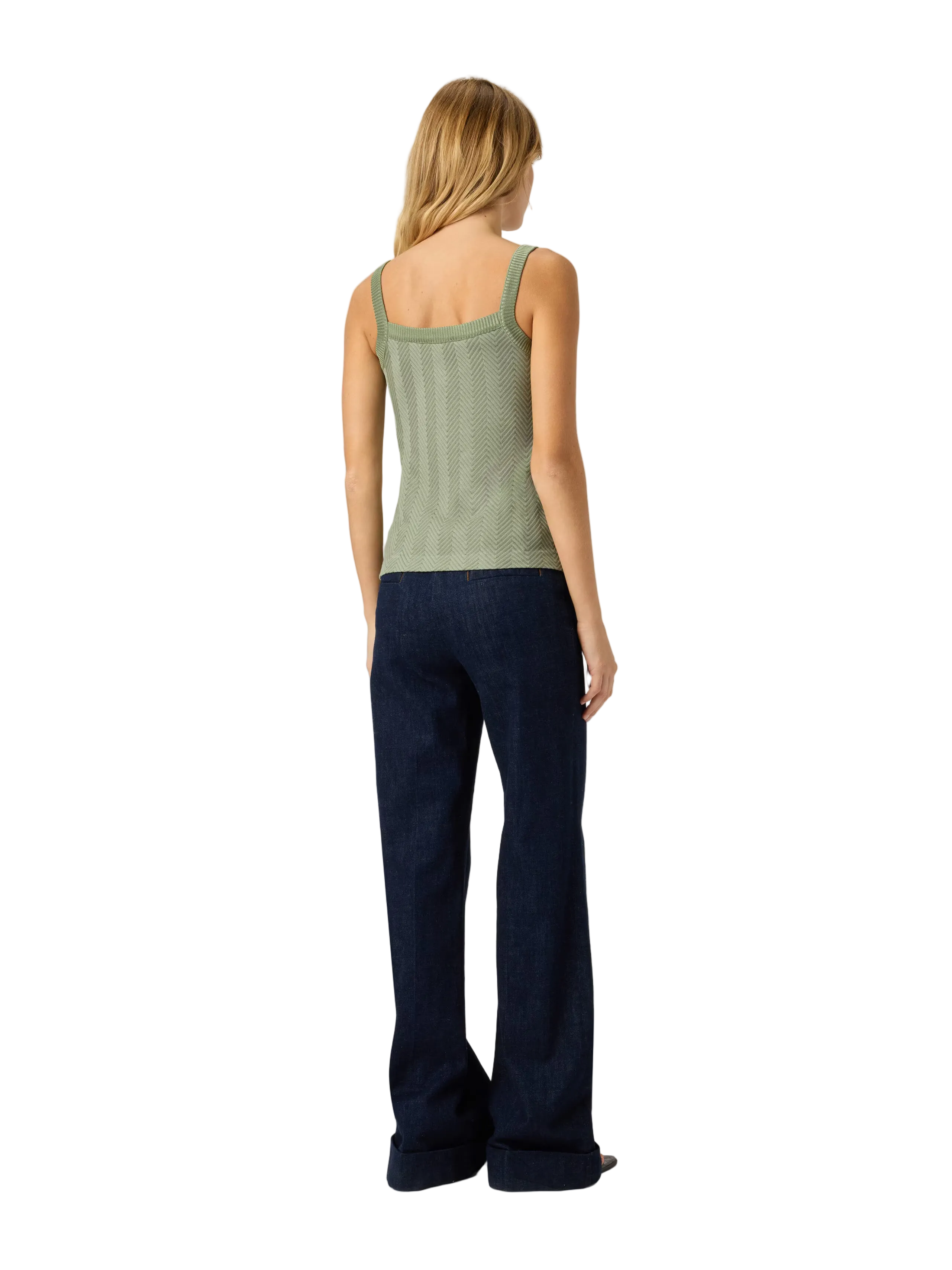 Woman wearing a green tank top and dark blue jeans on a white background