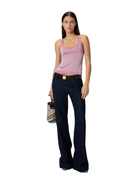 Woman wearing a pink tank top and dark blue jeans on a white background