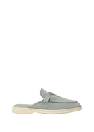 A light gray suede mule loafer with a small gold-tone horsebit detail on the strap, set against a solid off-white background.
