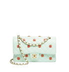 A light mint green quilted leather shoulder bag with red embroidered starburst motifs and a gold-tone chain strap, displayed on a clean white background.