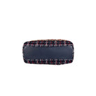 A small rectangular handbag with a navy blue leather front panel and a navy tweed body featuring red, white, and gold woven details, shown against a plain light gray background.