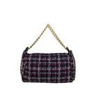 A small shoulder bag in navy blue tweed with red and white plaid lines, featuring a gold chain strap, shown against a solid light gray background.