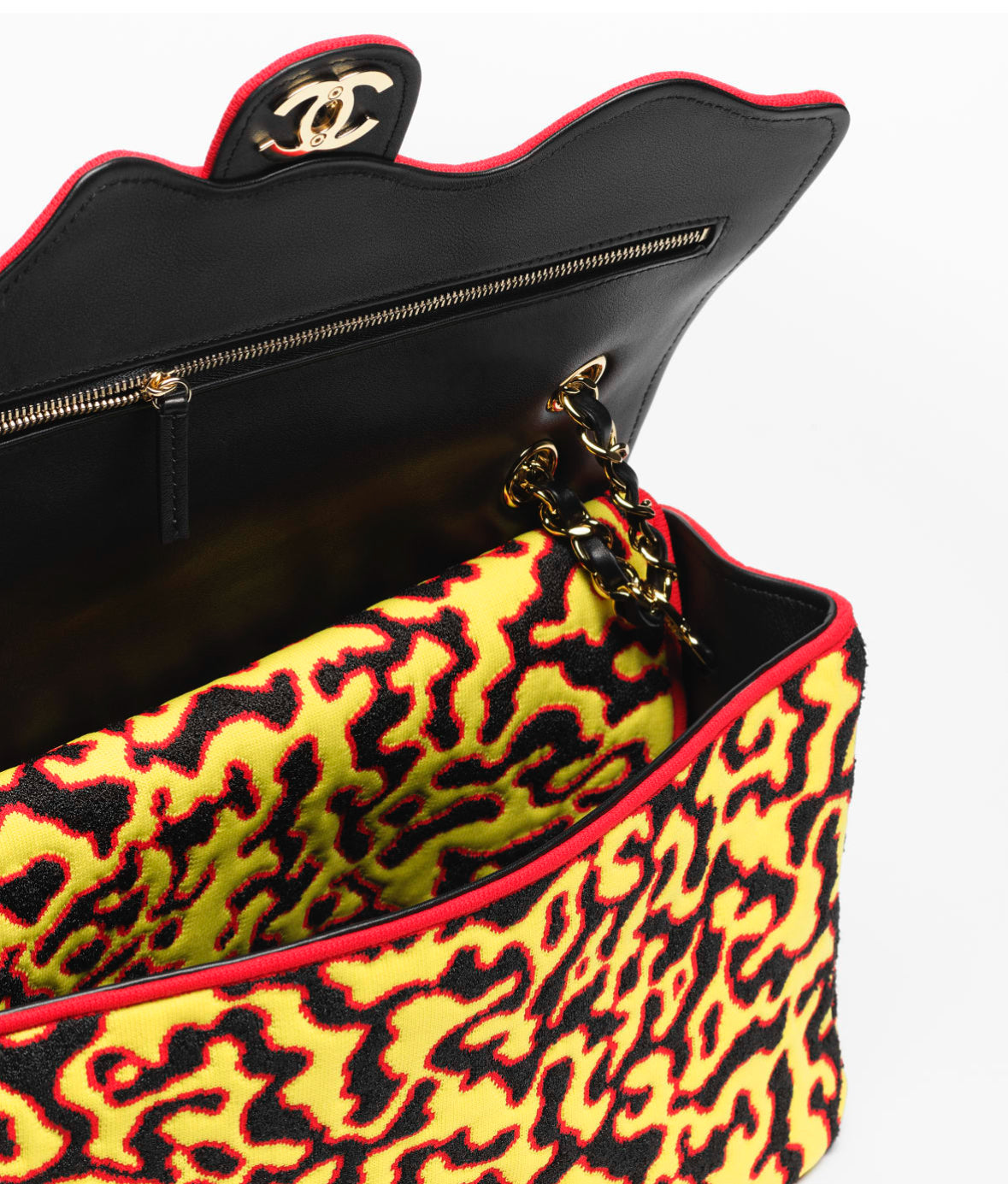 Chanel handbag with black interior and yellow leopard print exterior on a white background