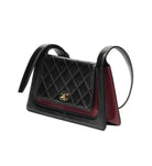 Black quilted handbag with gold hardware on a white background
