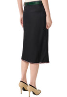 Black skirt with a green belt and beige shoes on a white background