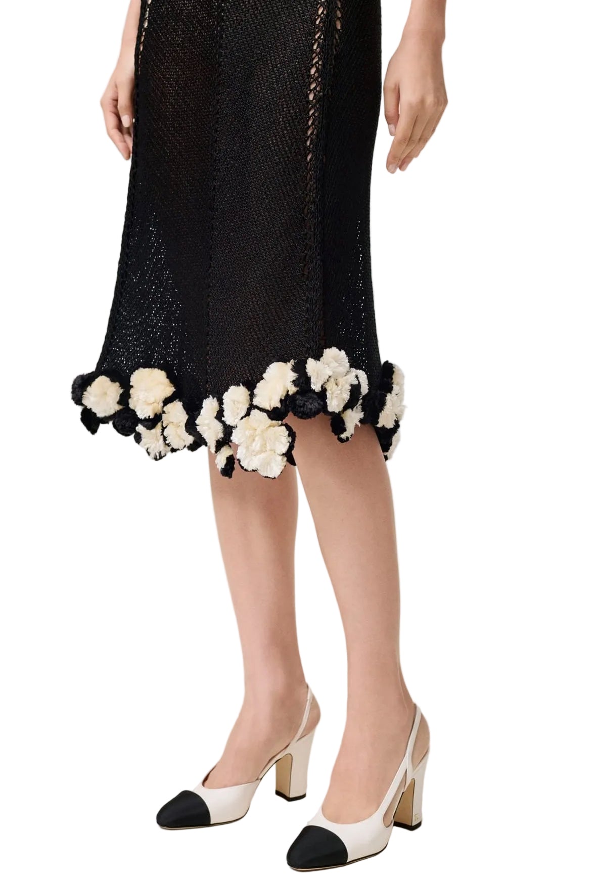 Black dress with floral details and black and white shoes on a plain background