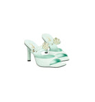 Mint green high-heeled shoes with floral embellishments on a white background
