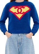 Person wearing a blue sweater with a Superman logo design on a white background