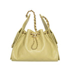 A light yellow quilted leather drawstring handbag with gold-tone hardware, featuring a double chain strap and a prominent interlocking CC logo on the front, set against a plain white background.