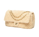 A beige faux fur quilted handbag with a gold chain strap and a gold interlocking CC logo on the front flap, photographed on a clean white background.