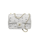 A silver pebbled leather handbag with a gold-tone chain strap and a gold interlocking CC logo on the front flap, photographed on a clean white background.