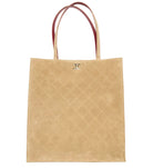 A beige quilted suede tote bag with dark reddish-brown leather handles and a gold-tone interlocking CC logo on the front, set against a plain white background.