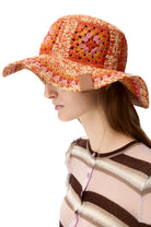 Woman wearing a colorful crochet sun hat on a white background