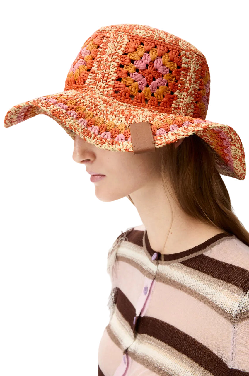 Woman wearing a colorful crochet sun hat on a white background