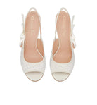 White high-heeled sandals with 'Christian Dior' branding on a light gray background