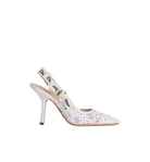 A white pointed-toe slingback high heel with floral laser-cut detailing on the toe and heel, featuring a Dior-embossed ankle strap, shown against a plain white background.