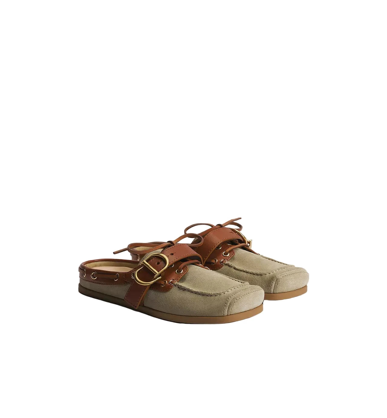 A pair of slip-on mule sandals in beige suede and brown leather, featuring decorative buckle straps and a low tan sole, photographed on a light gray studio background.