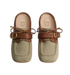 A pair of Dior mule loafers in light beige suede and brown leather, featuring double straps with bow details and gold-tone hardware, photographed on a light gray background.