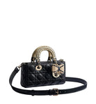Black quilted handbag with gold accents on a light gray background