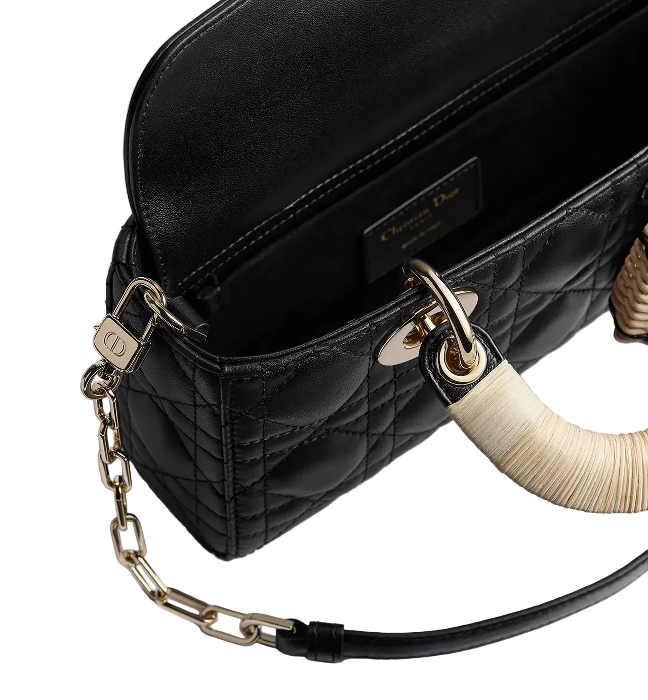 Black quilted handbag with gold chain strap and decorative handle on a light gray background