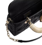 Black quilted handbag with gold chain strap and decorative handle on a light gray background