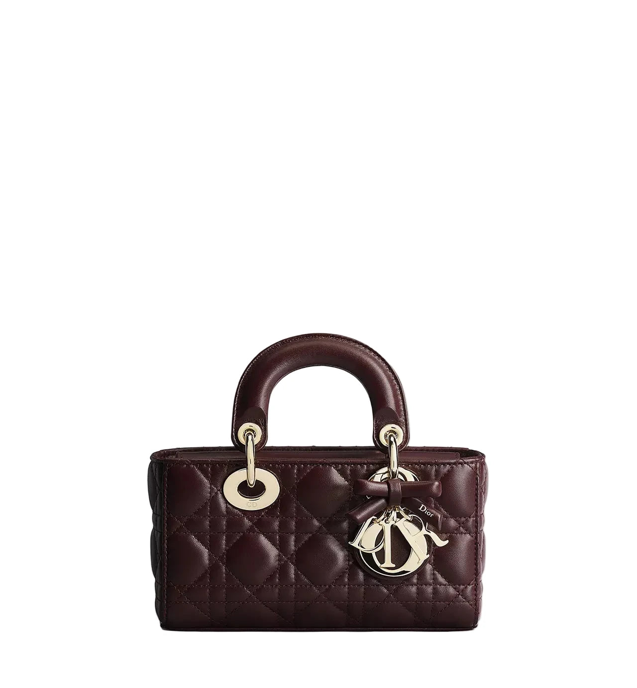 A dark burgundy quilted leather handbag with gold-tone hardware, featuring a top handle, circular ring detail, and a hanging Dior logo charm, set against a plain light gray background.