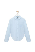Light blue shirt on a hanger against a white background