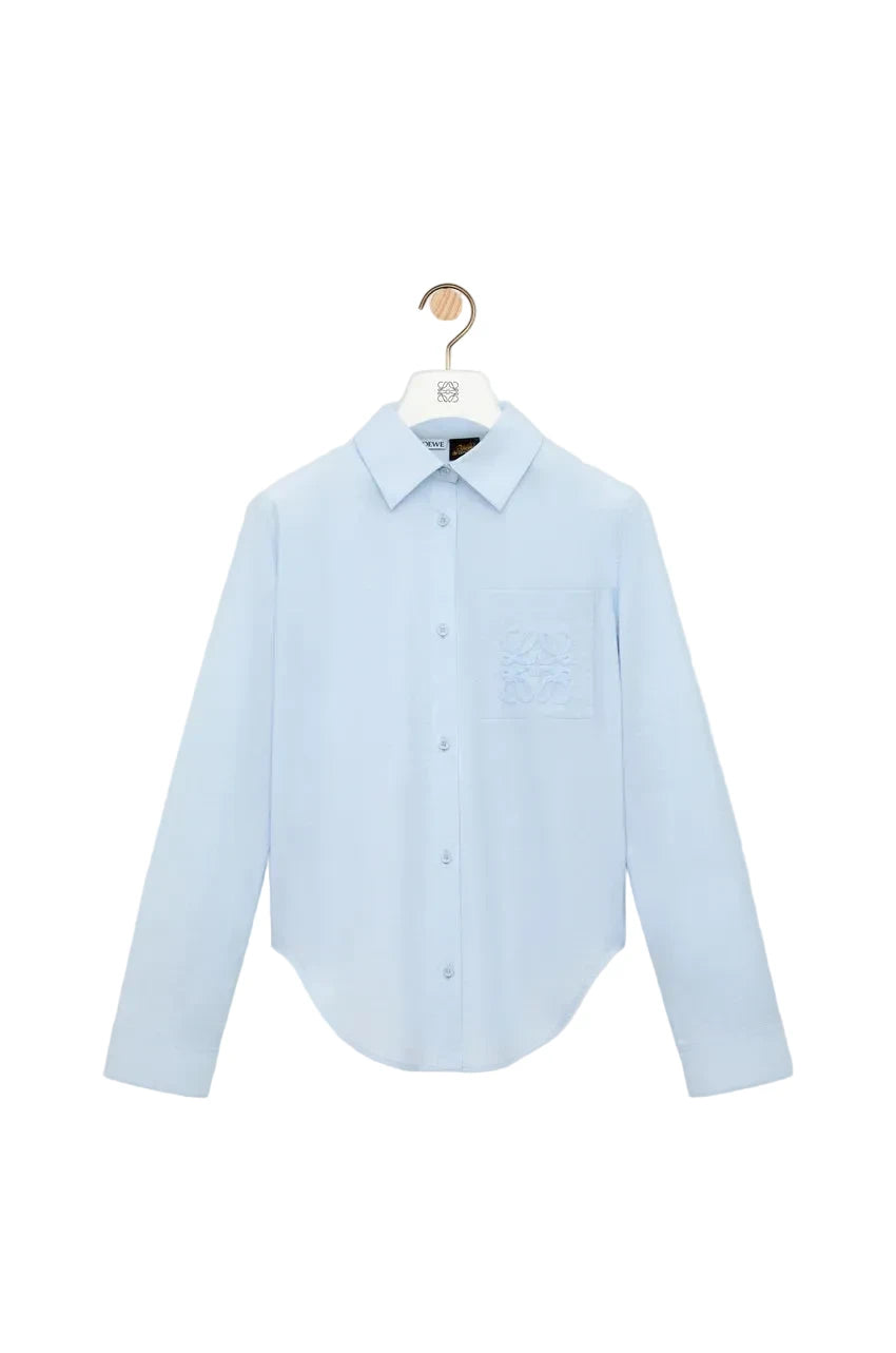 Light blue shirt on a hanger against a white background