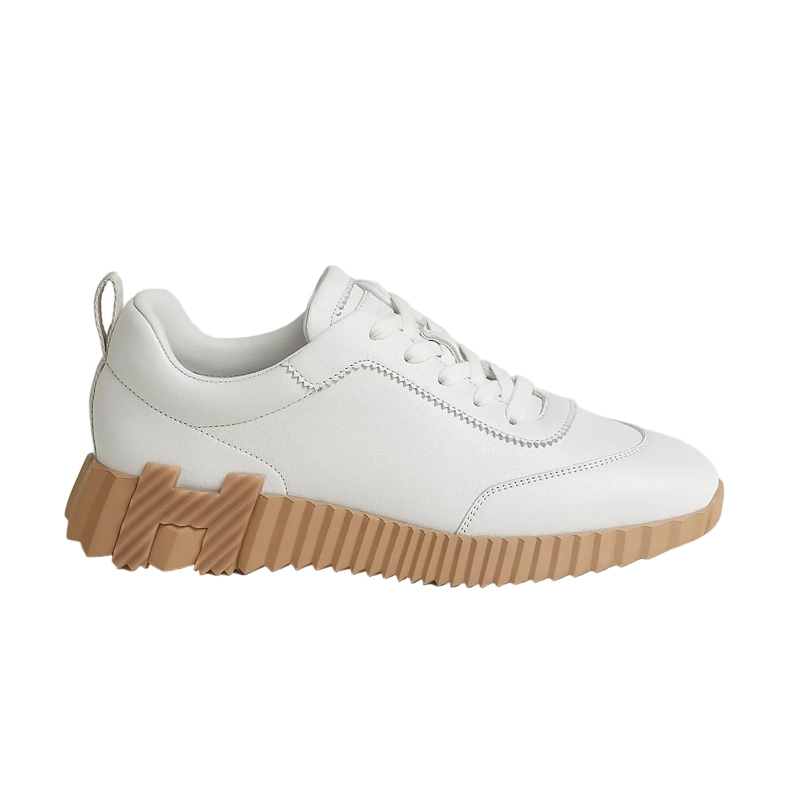 White sneaker with a brown sole on a light gray background