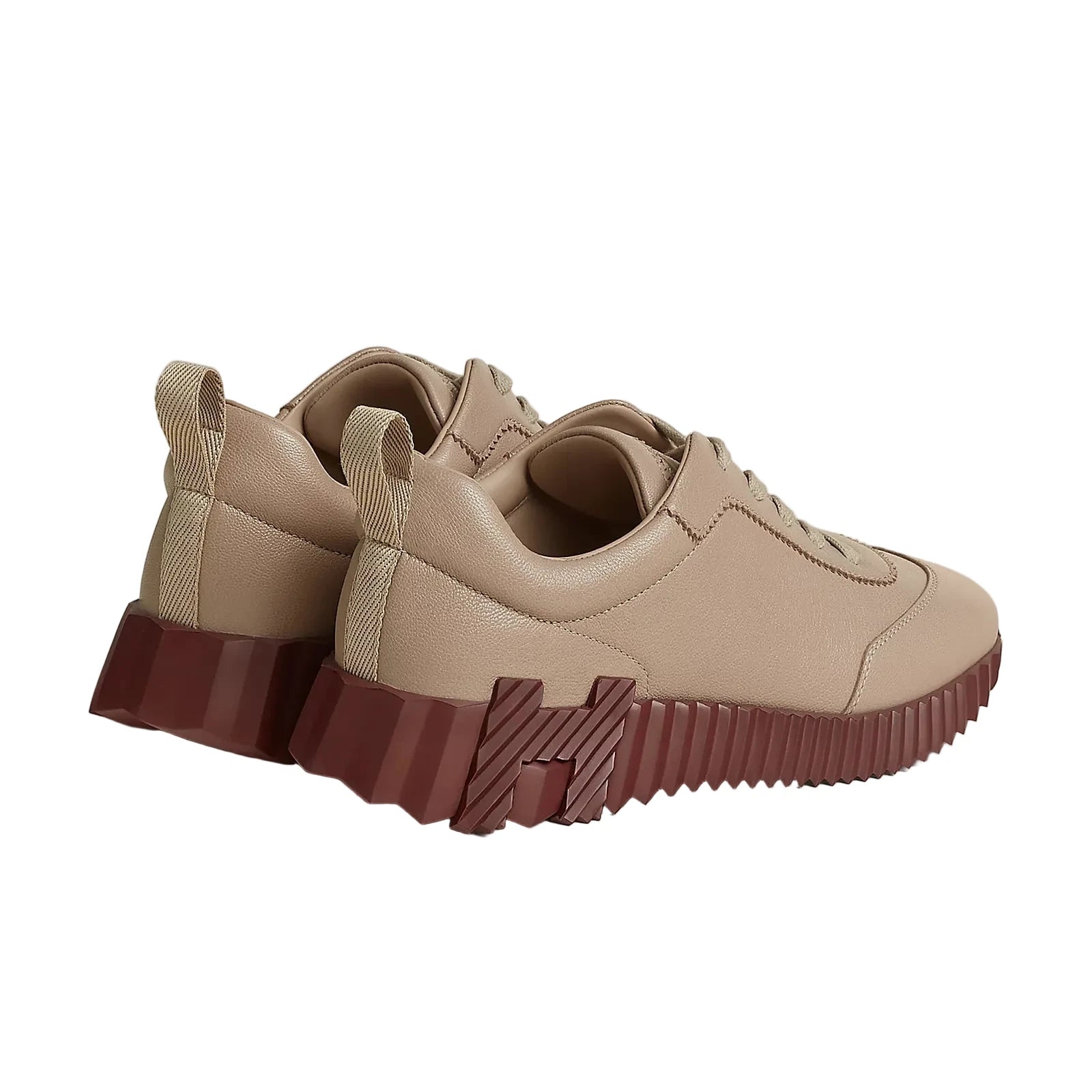 A pair of low-top sneakers in beige faux leather with chunky, ribbed burgundy soles, displayed on a light beige studio background.