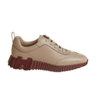 A low-top sneaker in light beige leather with a chunky, sculptural dark red sole, shown from a side profile on a light beige background.