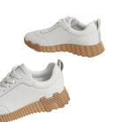 White sneakers with brown soles on a light background