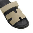Beige and black sandal with a prominent 'H' logo on a light background
