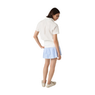 Woman wearing a white polo shirt and light blue skirt on a beige background