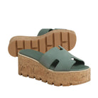 Green sandals with cork platform sole on a beige background