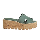 Green sandal with cork wedge sole on a light gray background