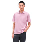 Man wearing a pink polo shirt against a light gray background