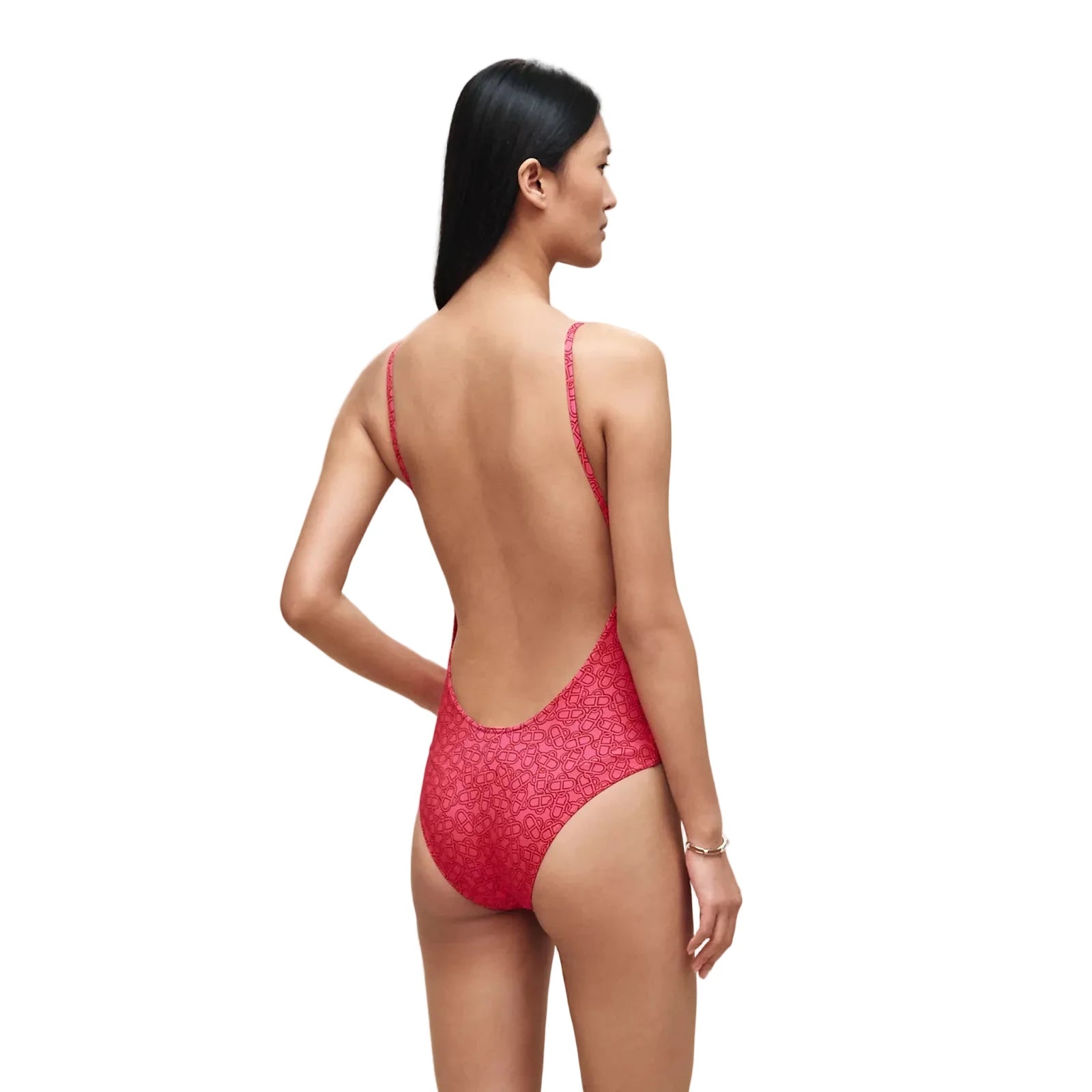 A woman modeling a red one-piece swimsuit with a small white floral pattern, shown from the back against a plain beige studio background.