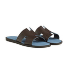 Pair of brown sandals with blue soles on a light gray background