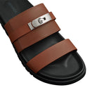 Brown and black sandal with a silver buckle on a light gray background