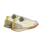 White sneakers with yellow accents on a light beige background
