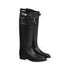 A pair of black leather knee-high rain boots with a decorative cutout pattern on the upper shaft and a silver buckle detail, shown against a light beige background.