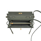 Green leather handbag with gold accents on a light gray background