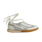 Sneaker with white laces and a brown sole on a light gray background