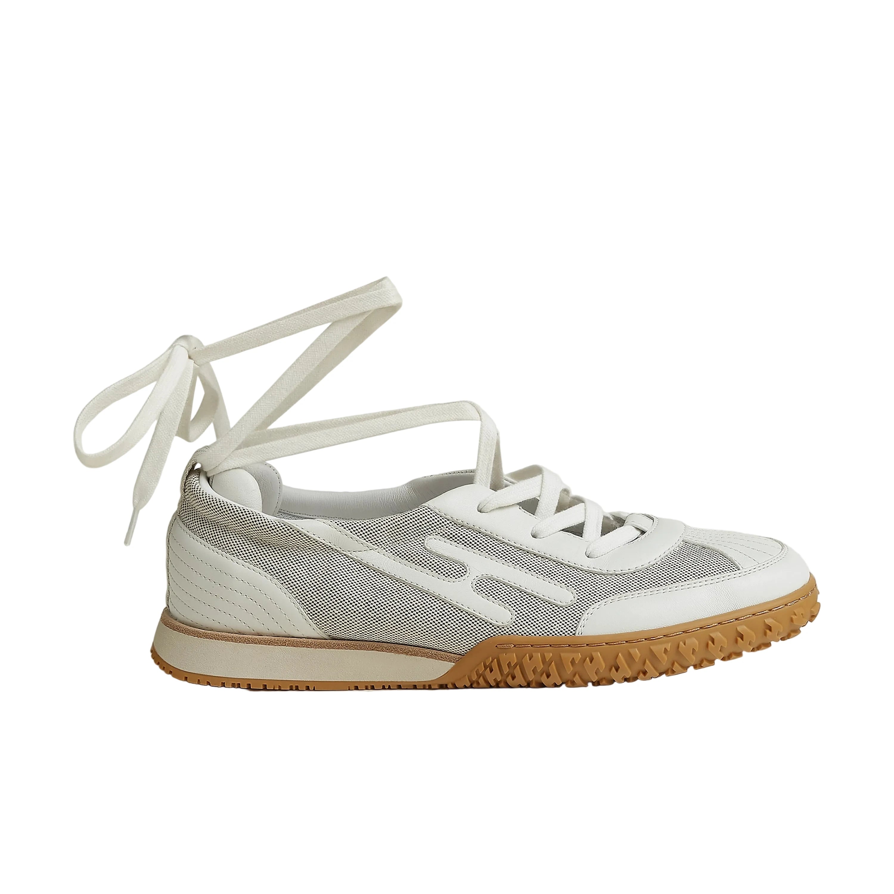 Sneaker with white laces and a brown sole on a light gray background