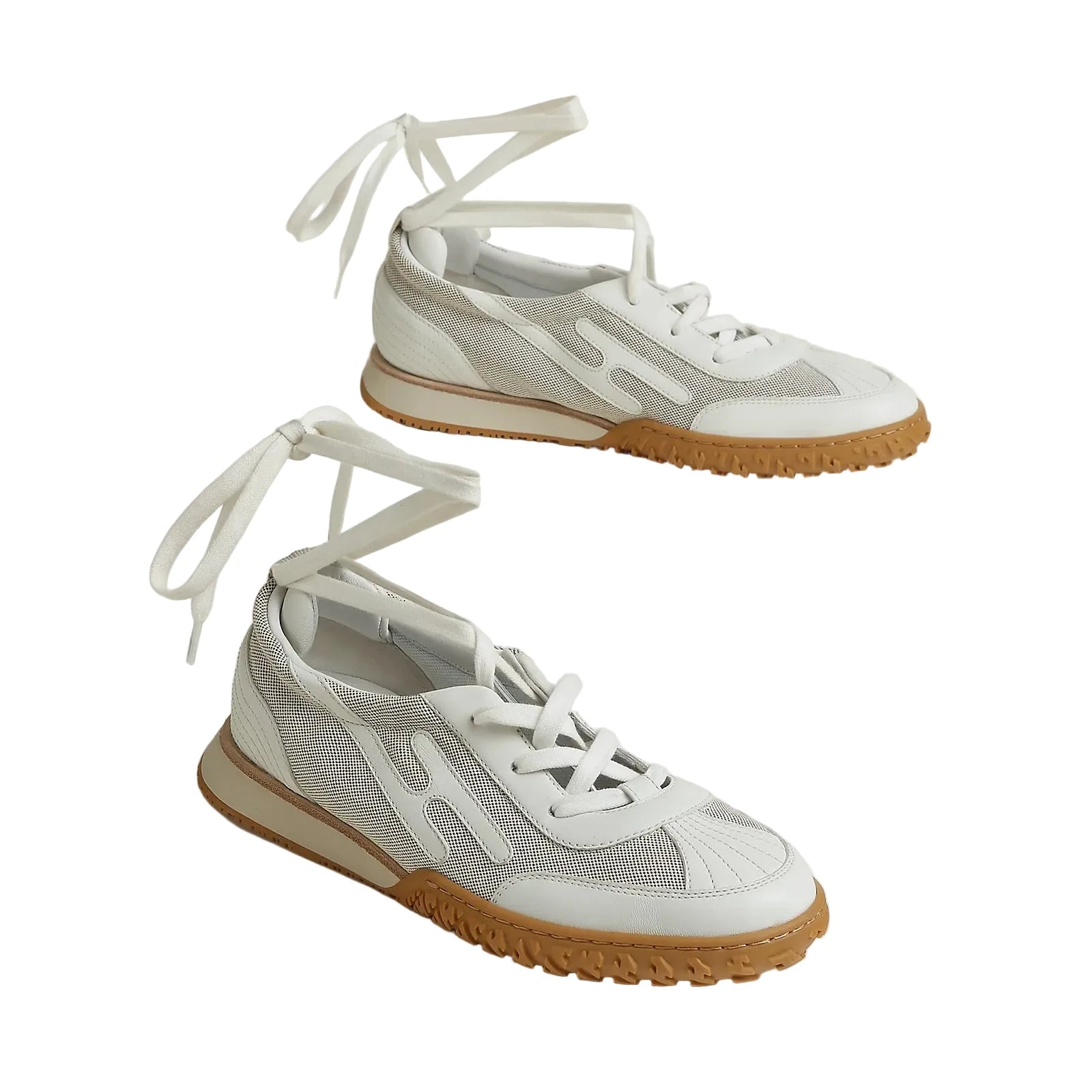 Pair of white sneakers with brown soles on a light background