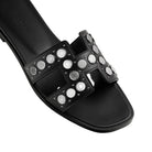 Black slide sandal with silver studs on a light gray background